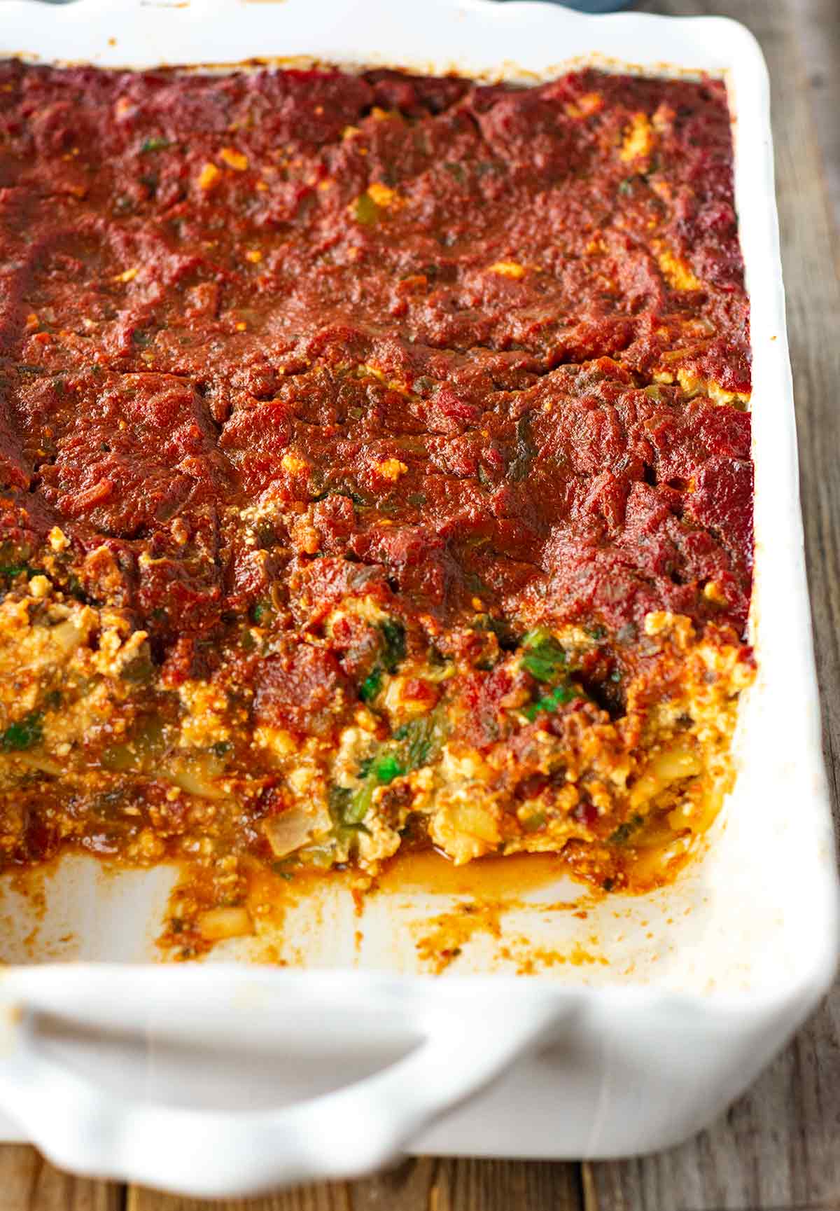 overlay lasagna in a white casserole pan on a wooden backgroun