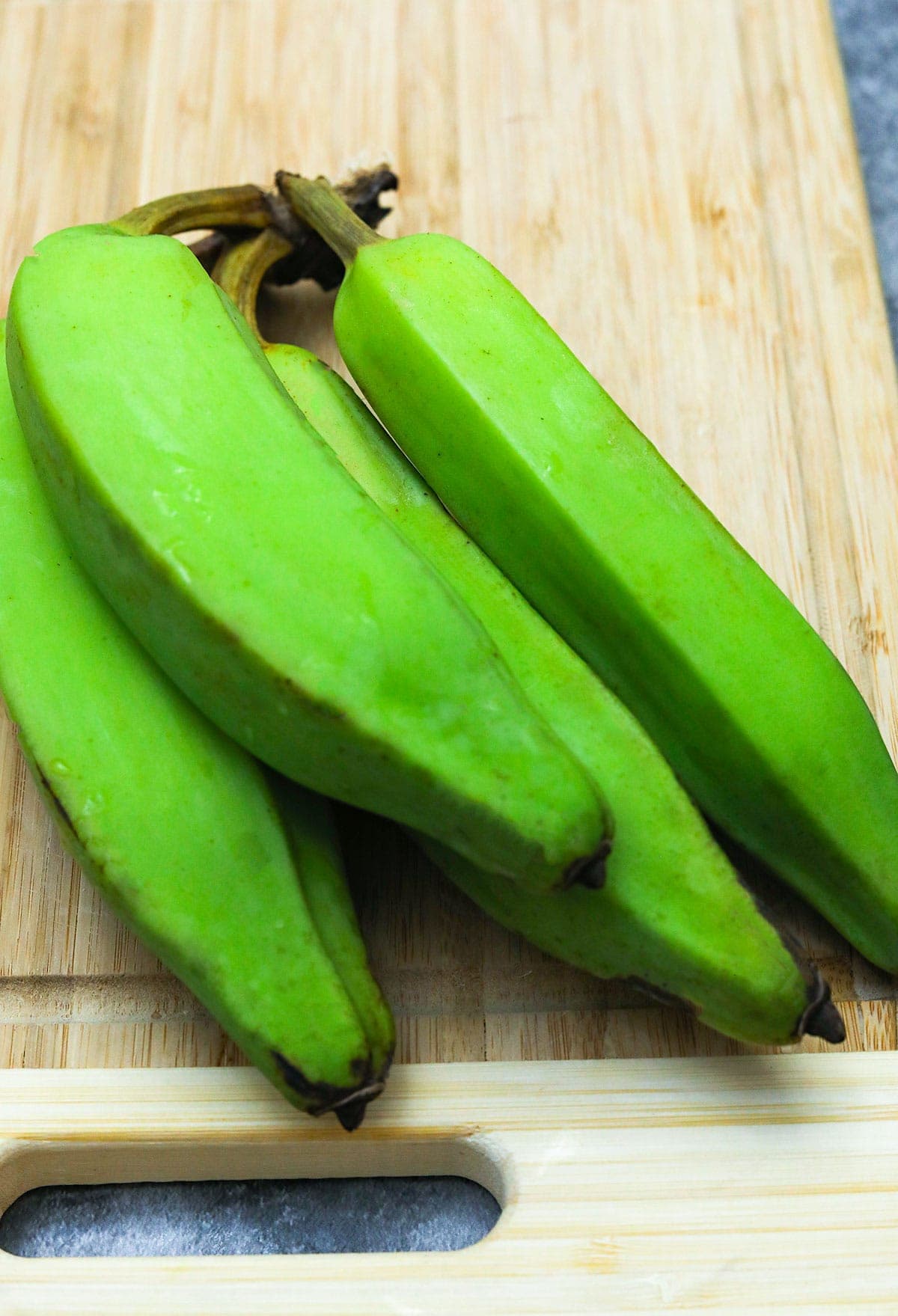 green bananas on cutting board