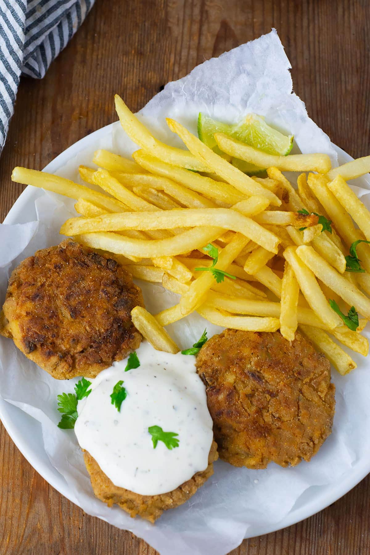 Overlay vegan crab cakes on a white plate with fries