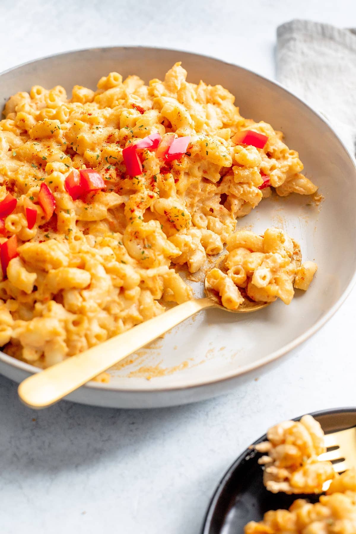 vegan mac and cheese in a white bowl with a spoonful on a white background