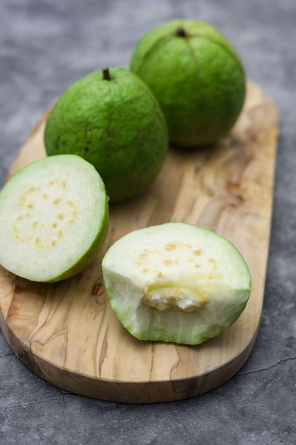 white guava on cutting board, one cut open to show its white flesh