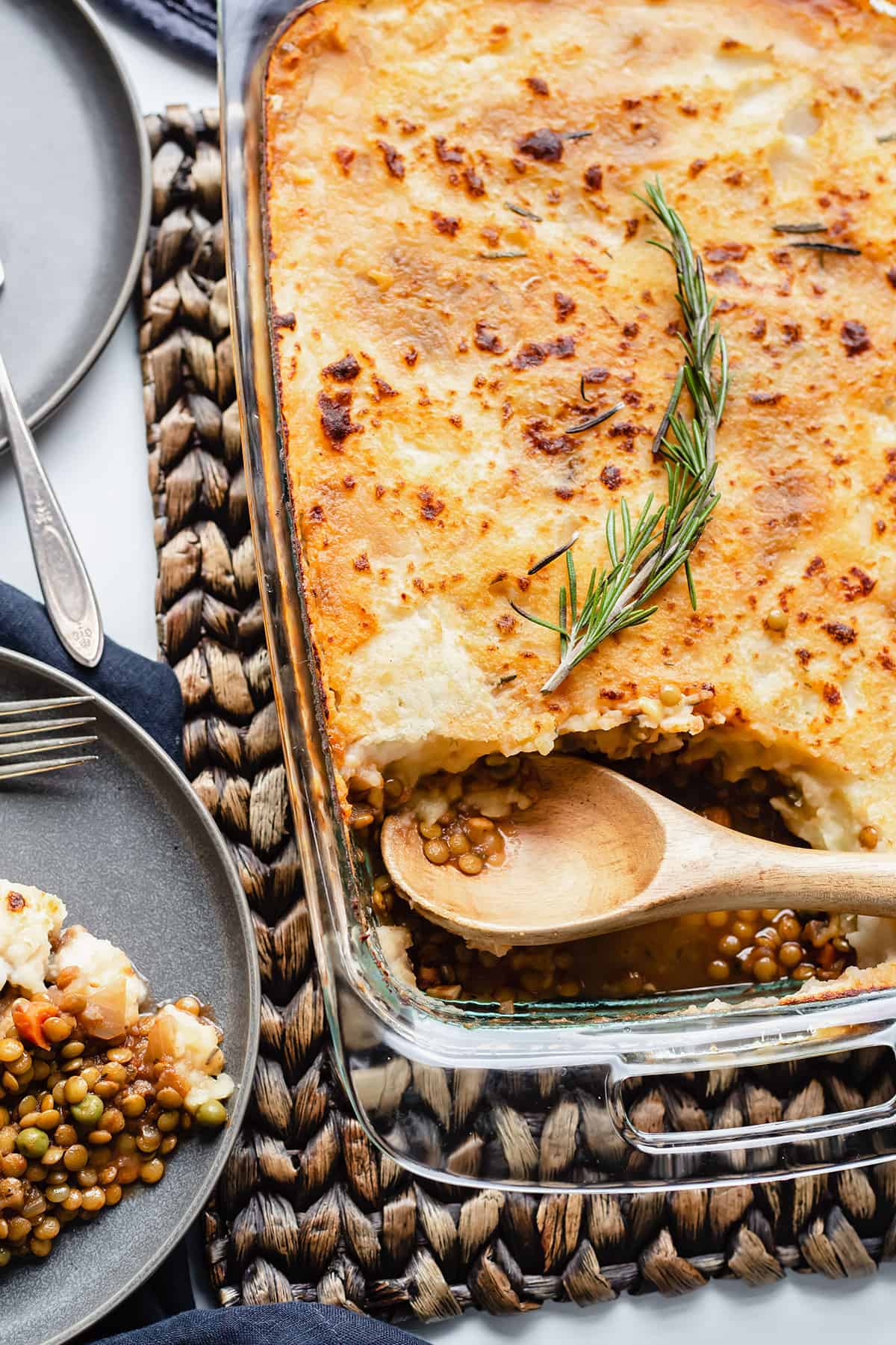 a shepherd's pie in a glass casserole dish with a piece taken out and a wooden spoon sitting in it