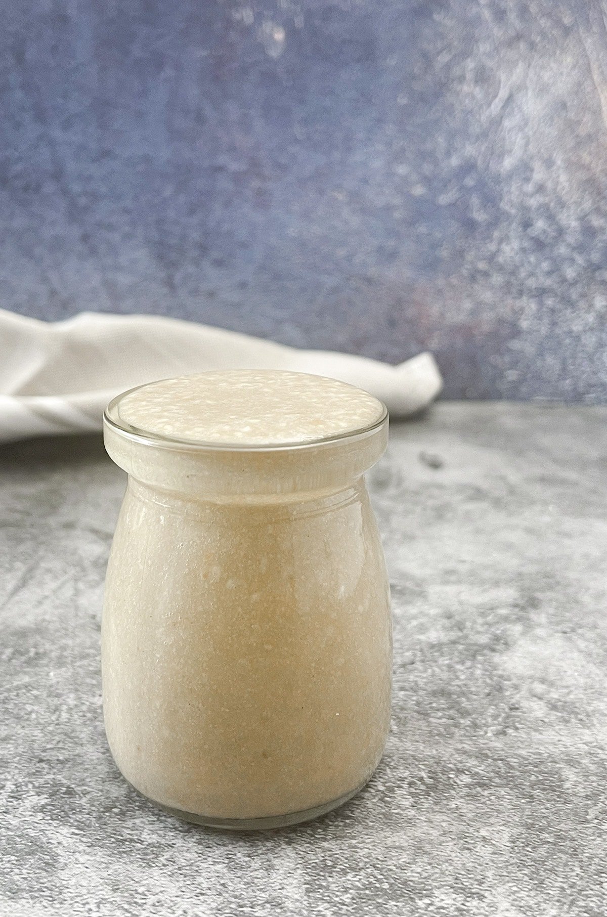 tahini from scratch in a glass jar on a grey background