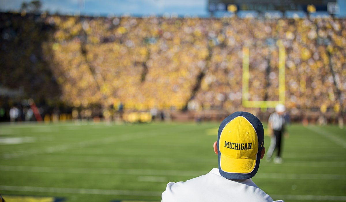 Michigan football fan looks on from crowd during game at Michigan Stadium