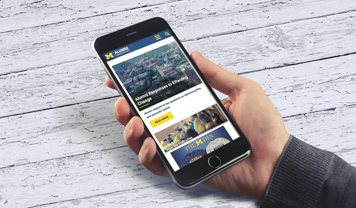 Someone holding an iPhone with the Alumni Association website displayed
