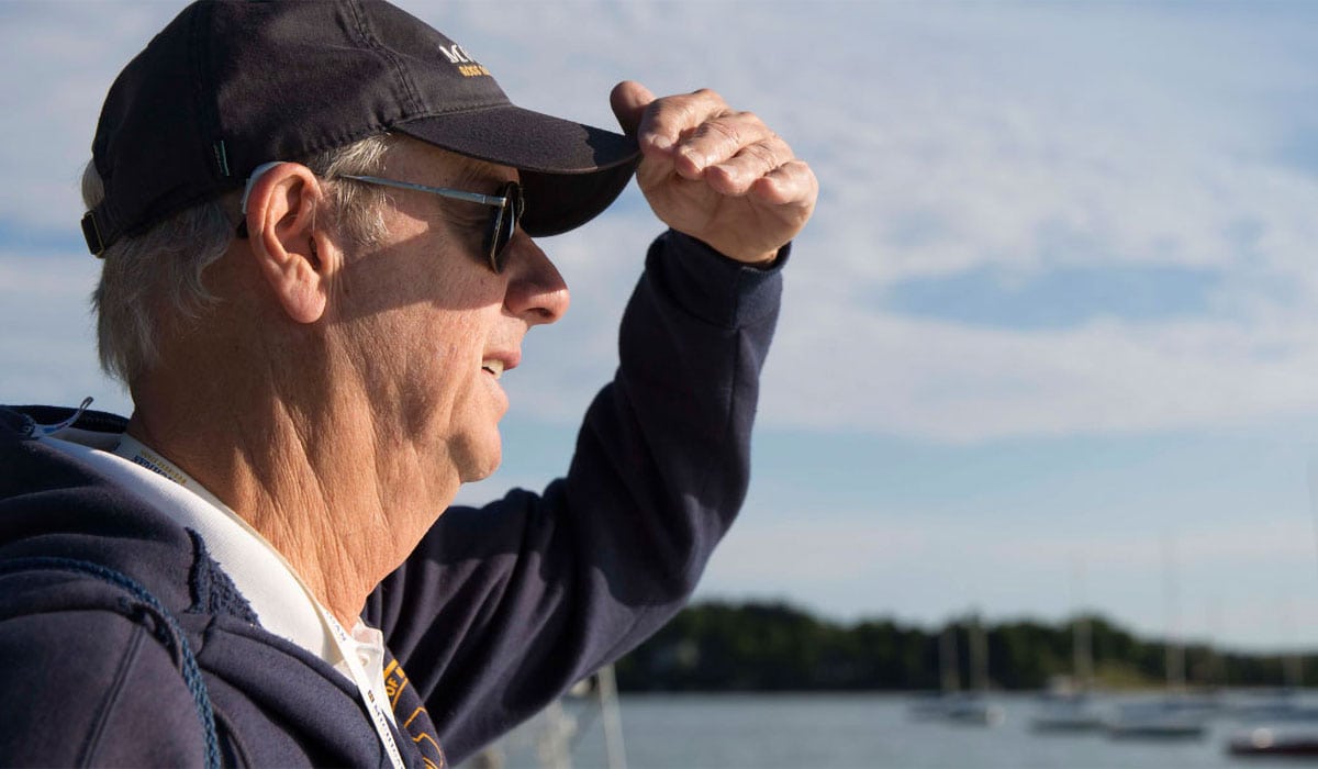Man looking out at sailboats on Walloon Lake at Camp Michigania