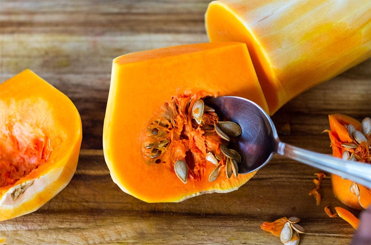 butternut squash on a wooden background being scoope with a spoon
