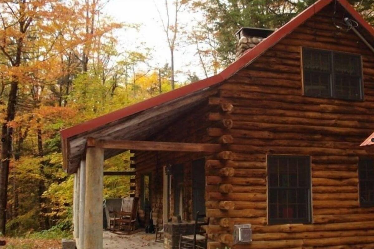 view of the outside of a log cabin surrounded by fall foliage near conway new hampshire