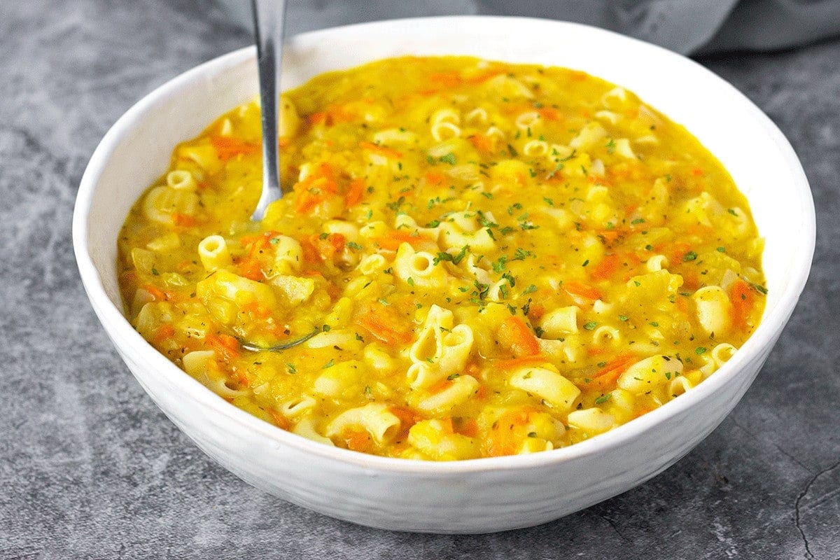 Vegan Instant pot red lentil soup with pasta and carrots overlay, in a white bowl with a spoon