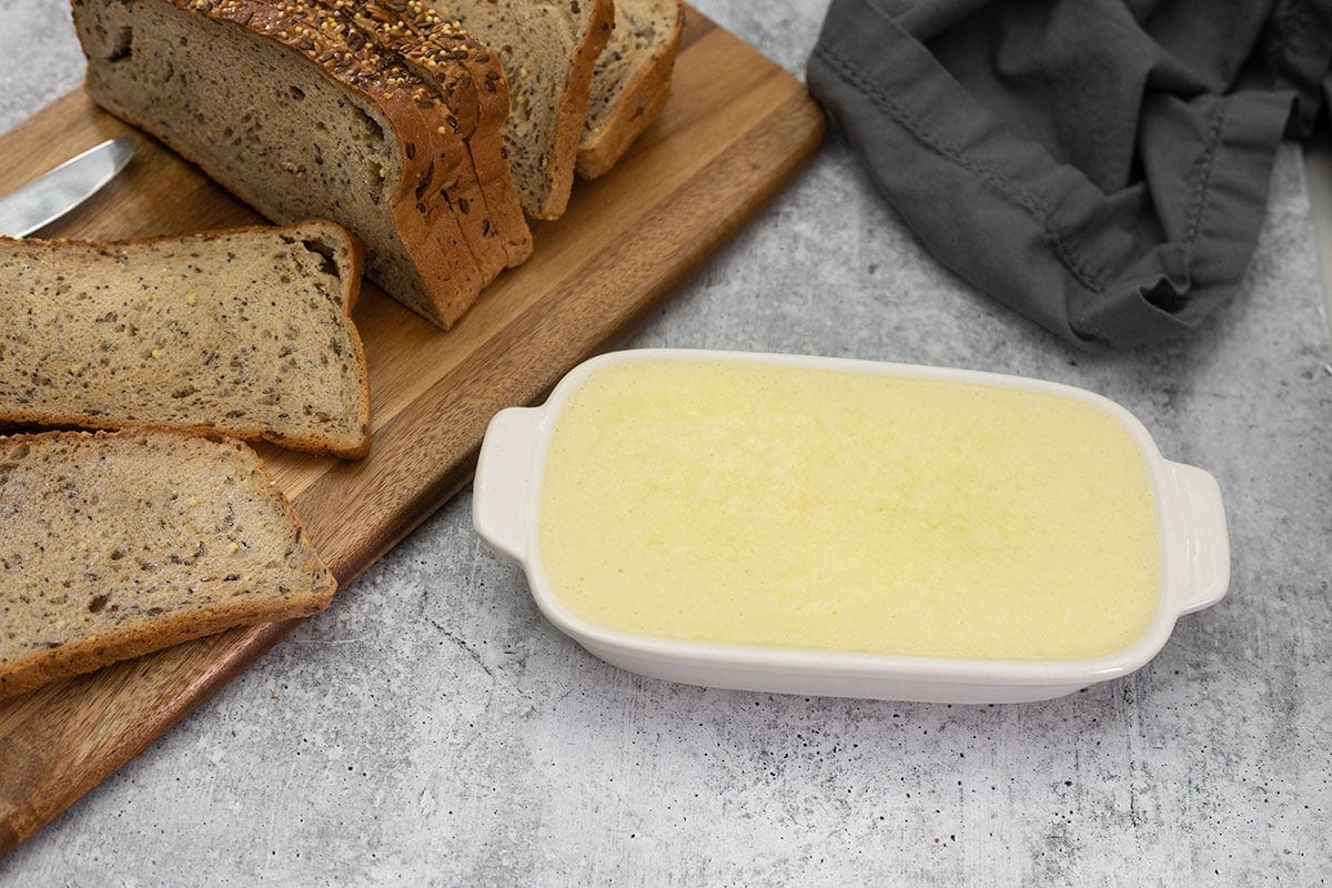 vegan butter in a white mold with a cutting board with slices of bread in the background
