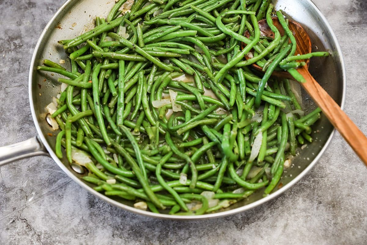 frozen green beans in saucepan on grey background