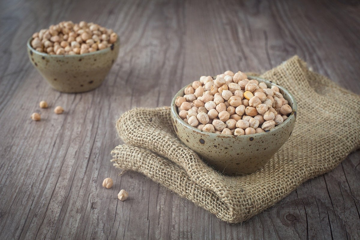 chickpeas in beige bowls on wooden background