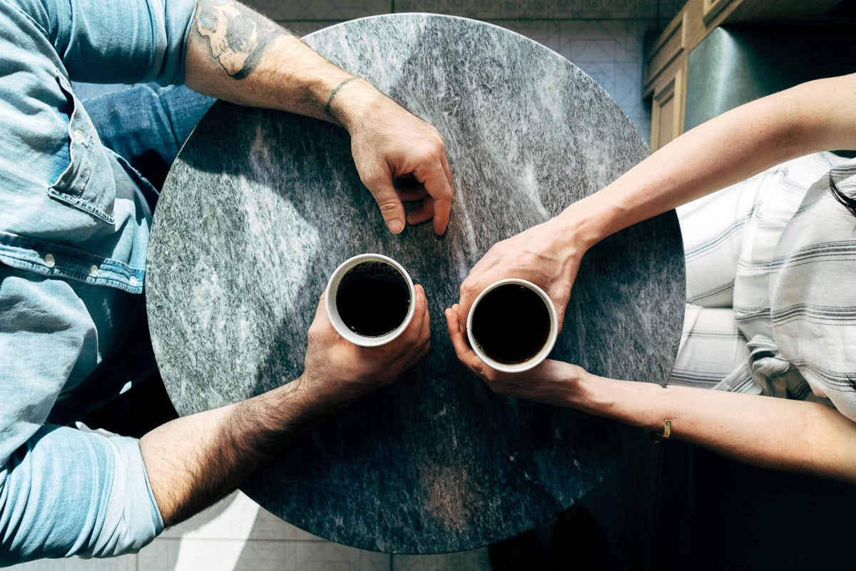 A couple sitting together and drinking coffee.