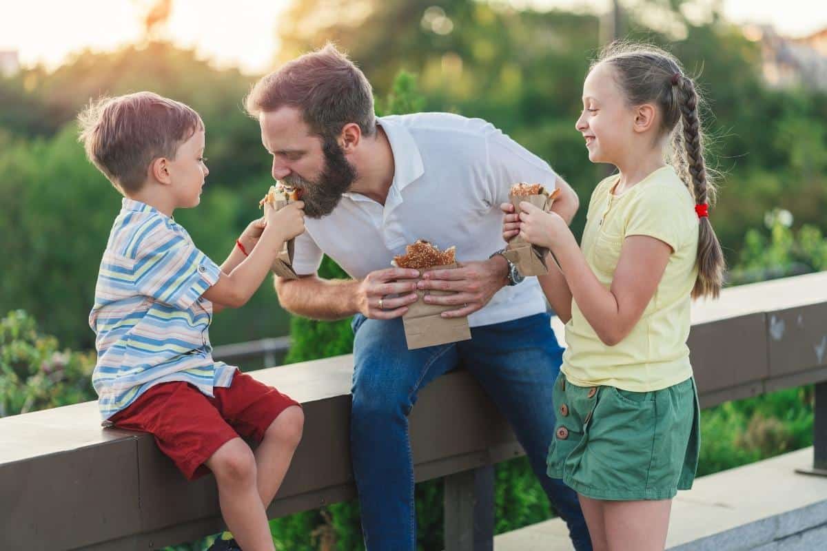 Family eating burgers outside.