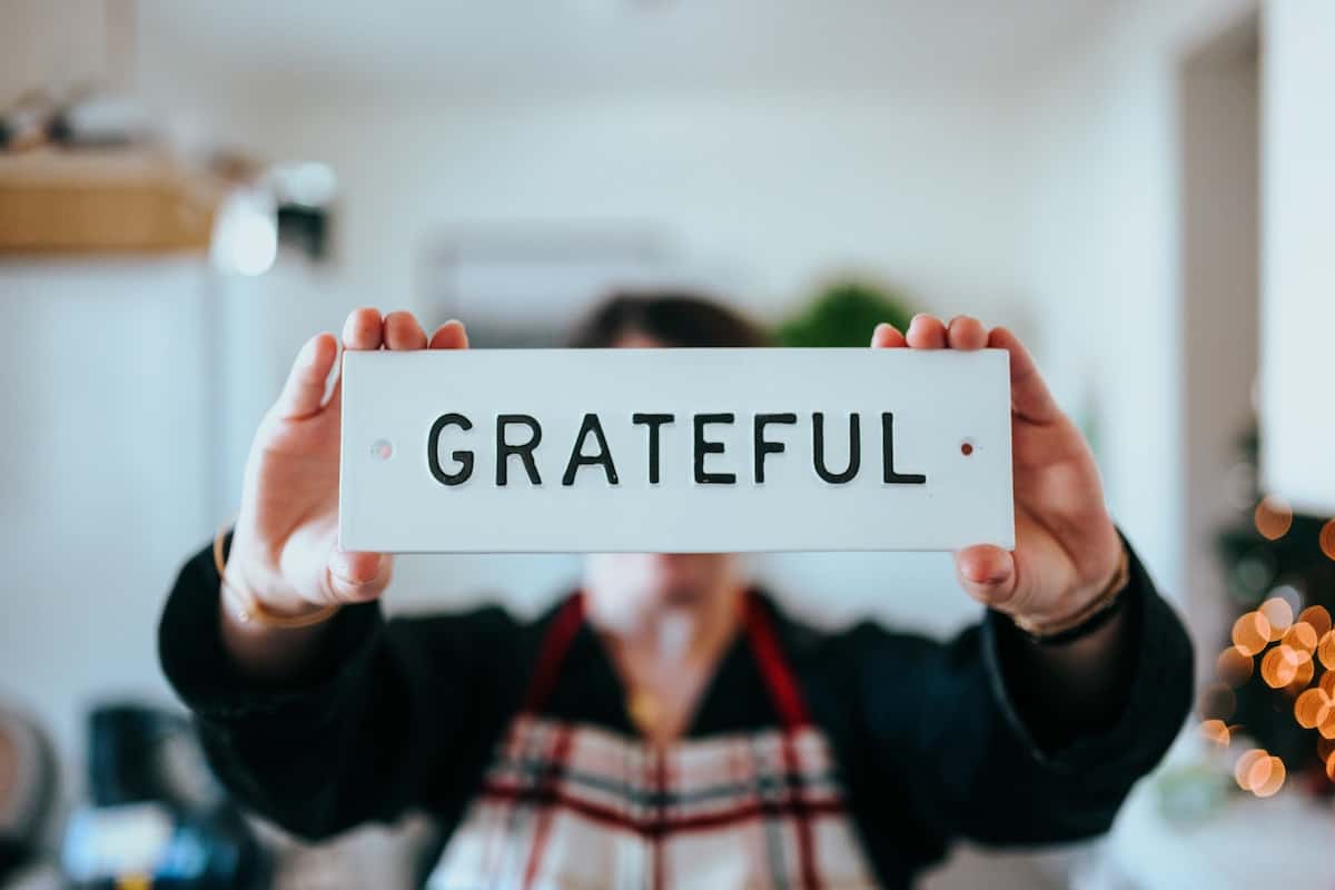 person holding sign in front of face that says "grateful"