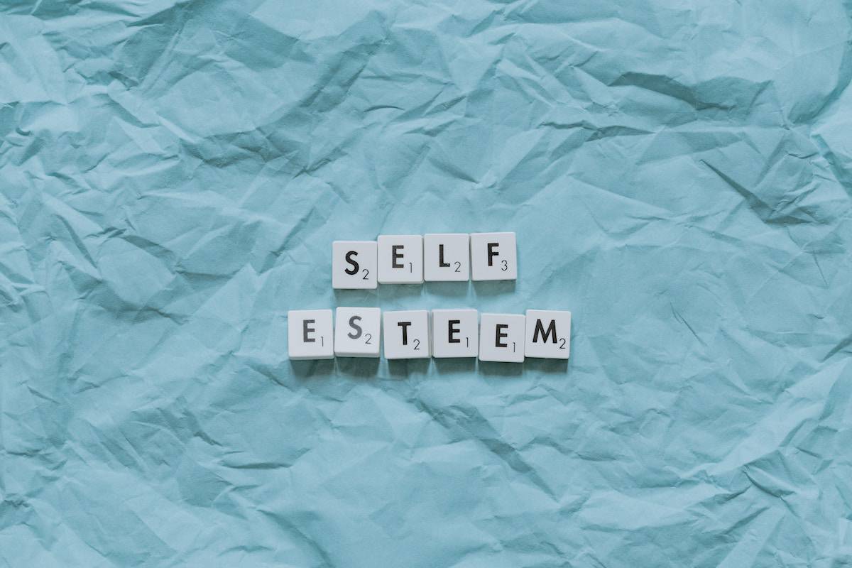 "self esteem" in letter blocks on blue crumpled paper background