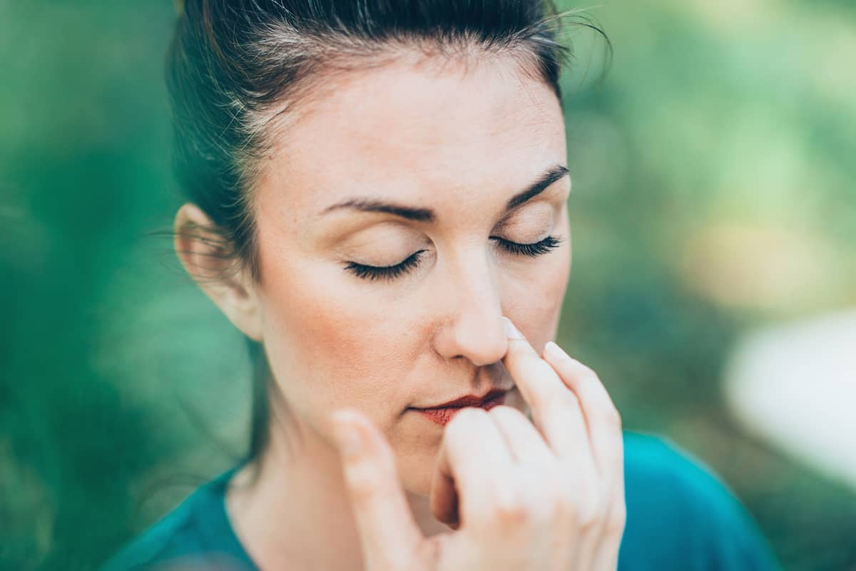 close up of woman doing alternate nostril breathing (Nadi shodhana pranayama)