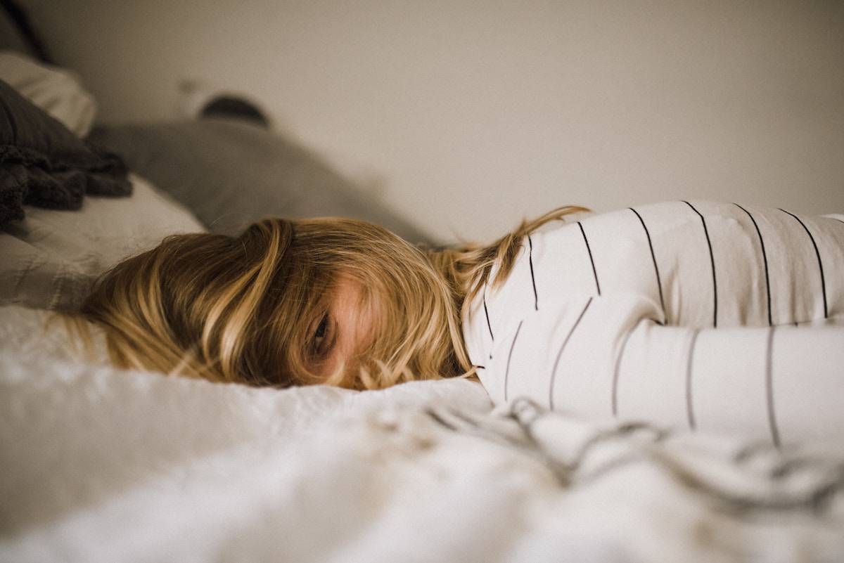 woman lying face down on bed