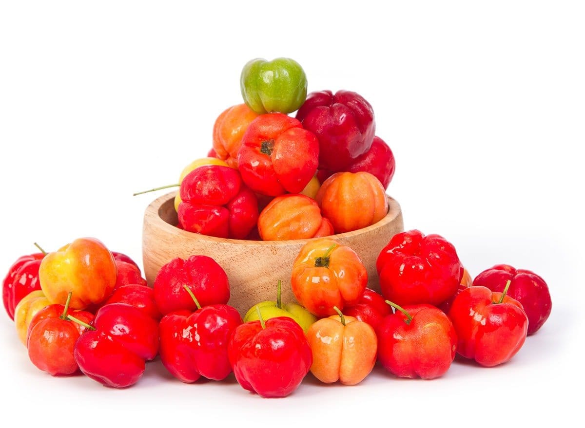 barbados cherries in a wooden bowl on a white background