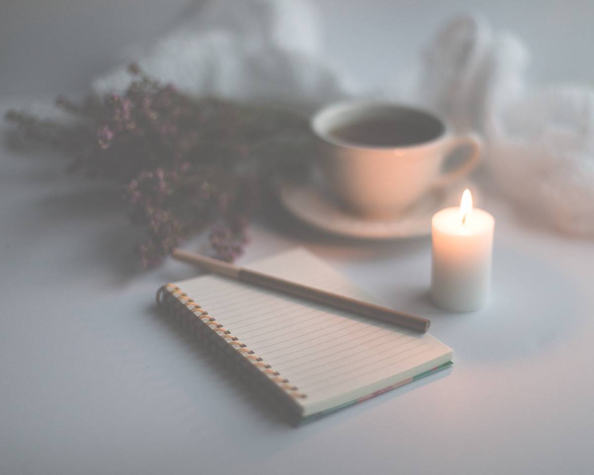 faded image of a journal next to a coffee and candle