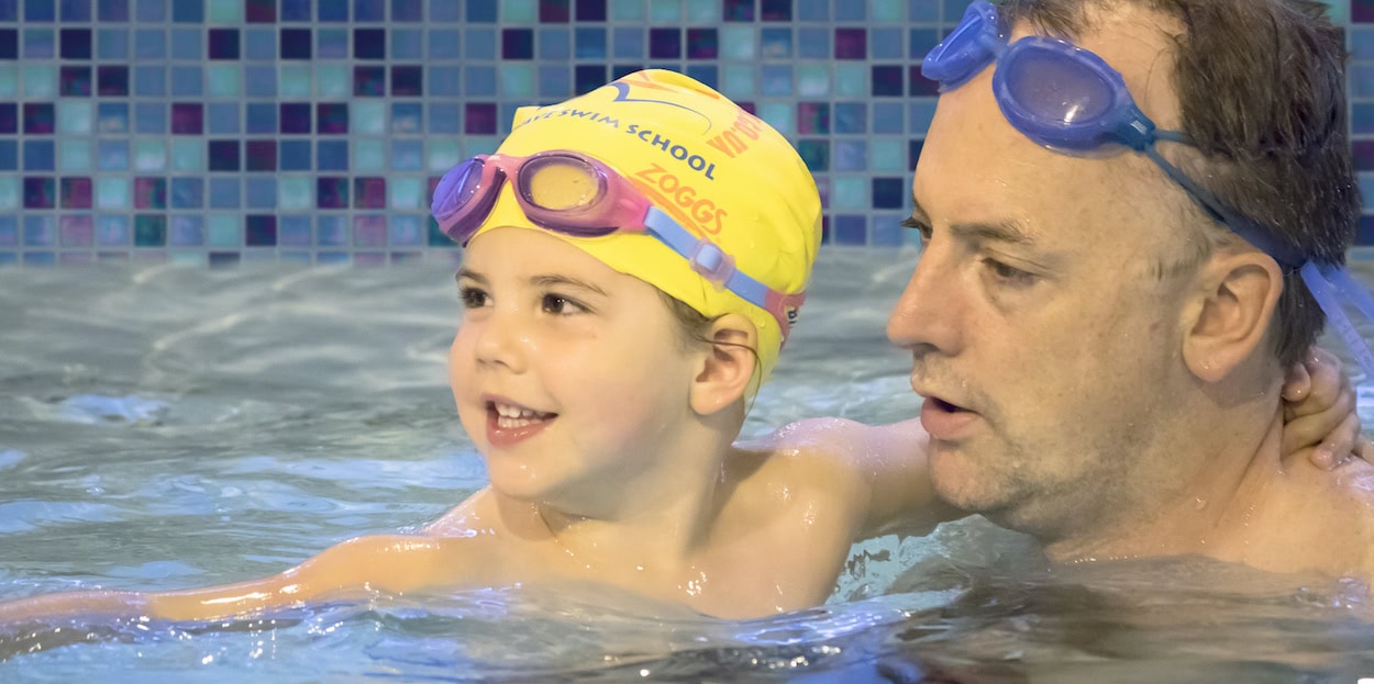 a 3 year old in toddler swimming class with father at Blue Wave Swim School