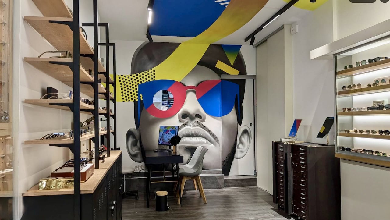 Fresque murale dans le magasin de l'opticien Stras Optic à Strasbourg : portrait géant à lunettes rouges et bleues au fond de la boutique