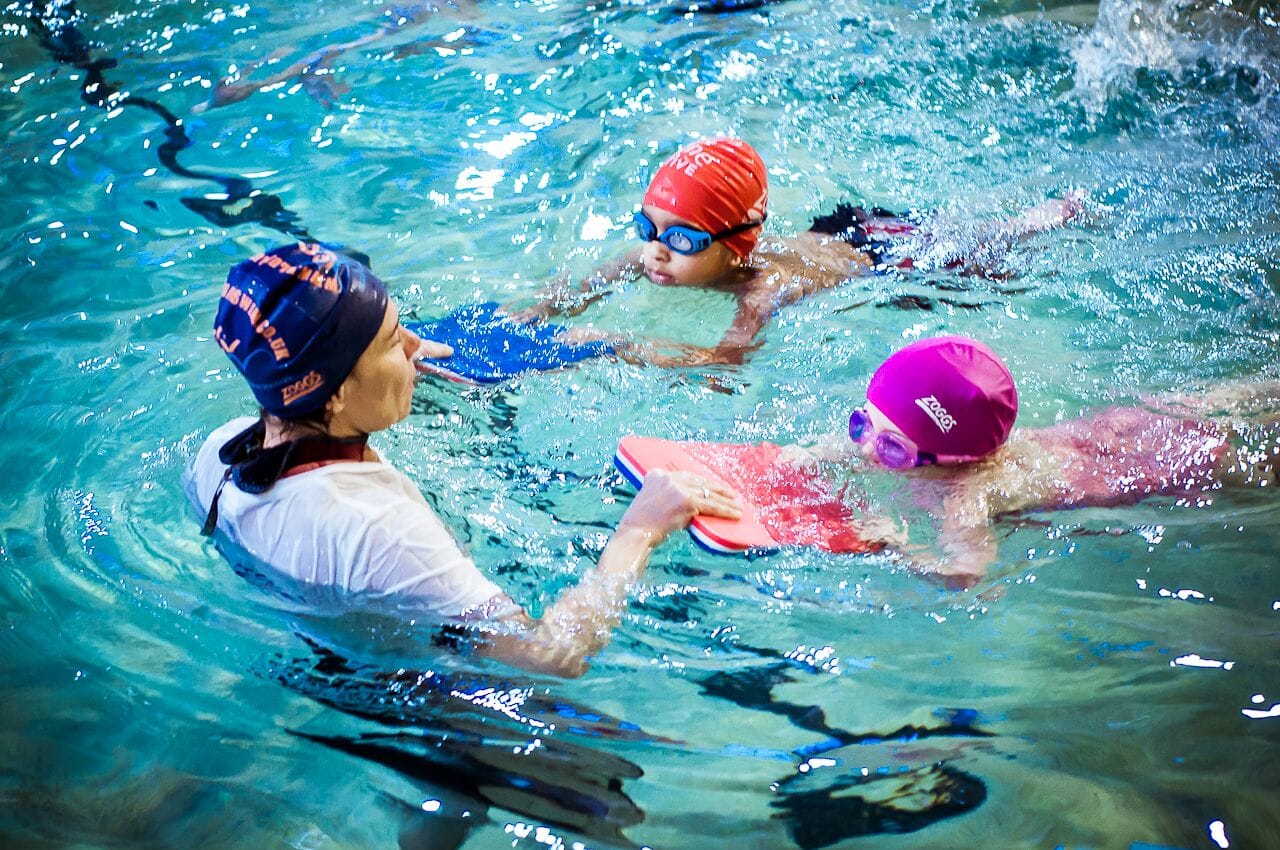 Blue Wave instructor teaches children in a semi-private lesson in an indoor pool using floats.