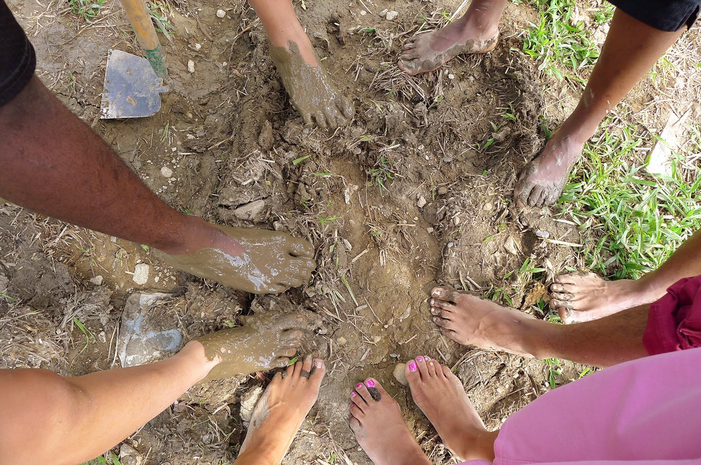Teen participants take their shoes off to experience the mud on their feet.
