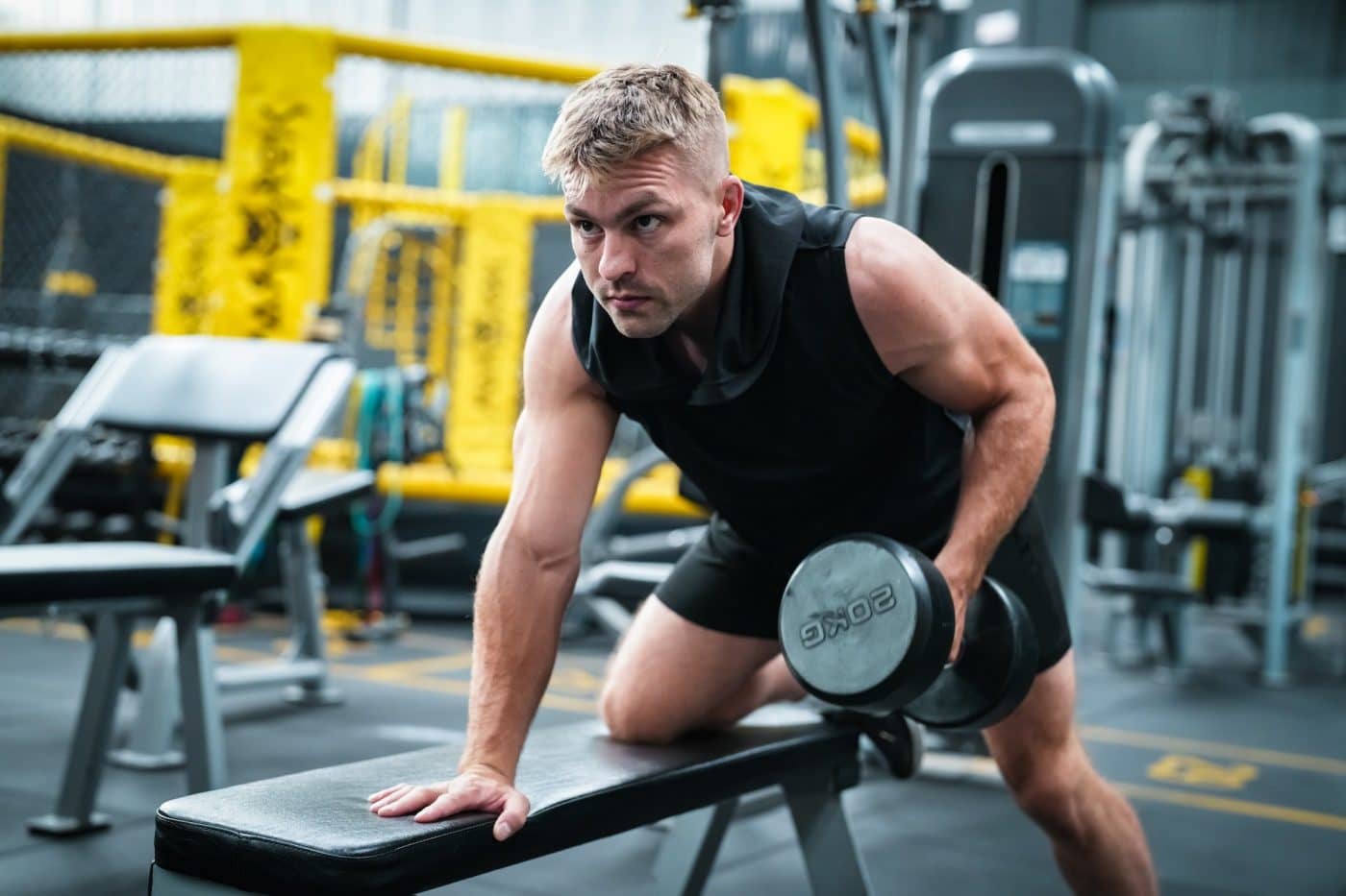Male athlete exercising in the gym, lifting weights, pulling joints.
