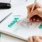 person writing on a spiral notebook