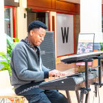 Musician seated and playing an electronic keyboard indoors