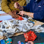 Workshop participants work together on a red patterned fabric frame at Galleria Shopping Mall.