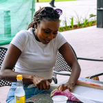 Participant carefully cuts fabric at a workshop table during the Frame and Fabric Workshop.