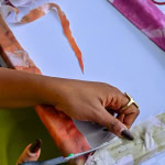 Close-up of a participant trimming and pinning fabric around a frame at the Galleria workshop.