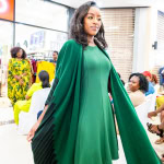A model showcases a flowing emerald green outfit during the Style, Shop & Sip fashion presentation