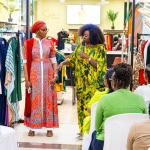 Connie Oluoch presents a patterned outfit beside a model while guests watch at Style, Shop & Sip.