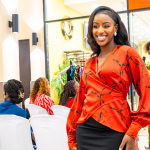 A smiling guest poses in a red blouse and black skirt at Style, Shop & Sip with Connie Oluoch.