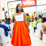 A fashion participant models a white top and bright orange skirt during Style, Shop & Sip