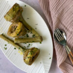 Sauteed Artichokes on a white plate with a pink napkin and servings spoon