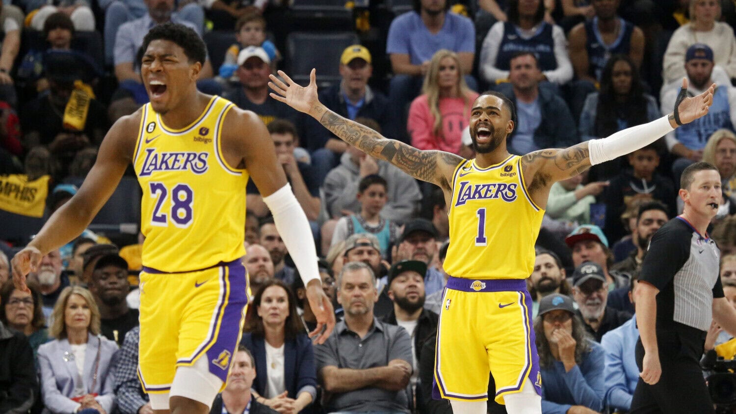 Basketball player D'Angelo Russell celebrates on the court with his arms spread outward while Rui Hachimura walks in the foreground ahead of him