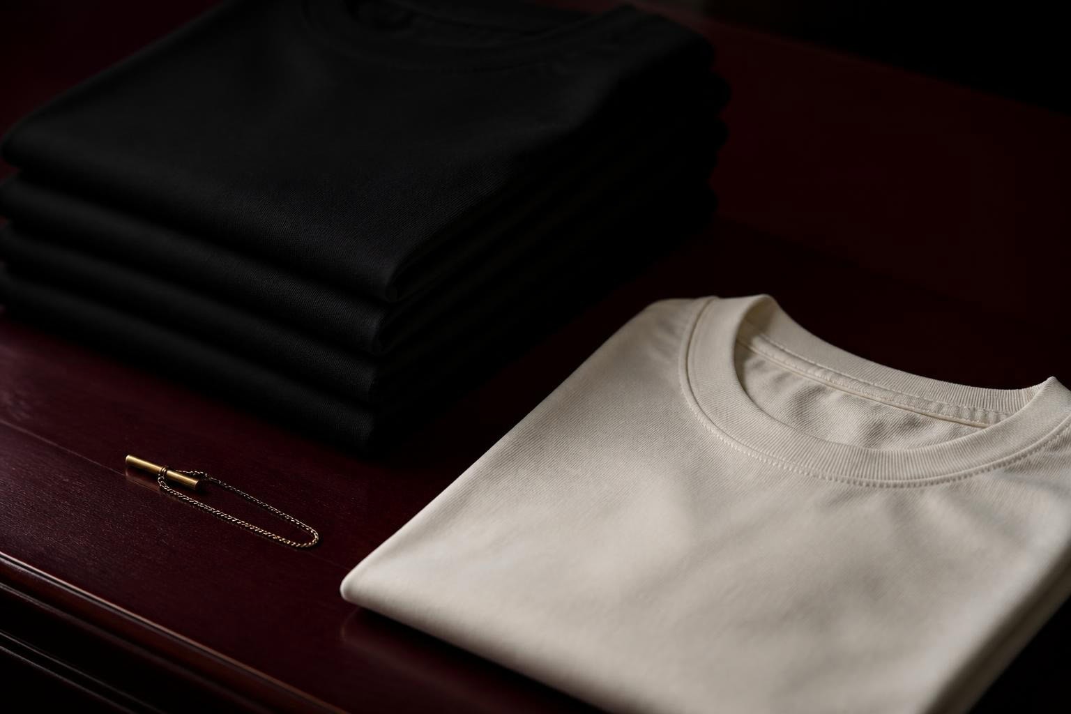 Folded black and ivory cotton on a wine-dark table