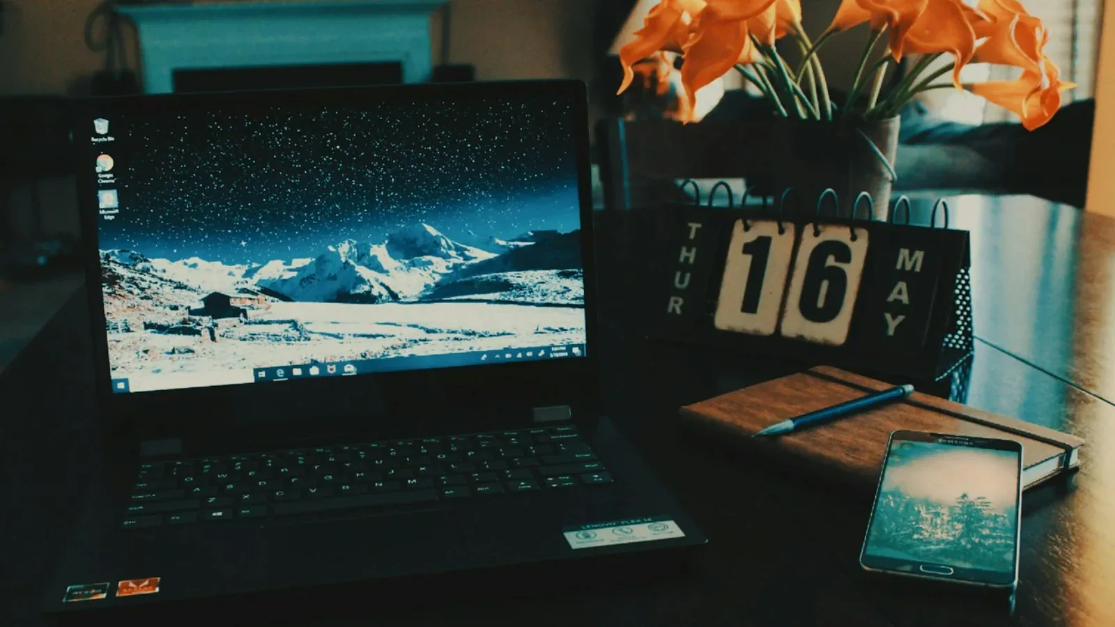 black laptop computer turned on on table beside phone