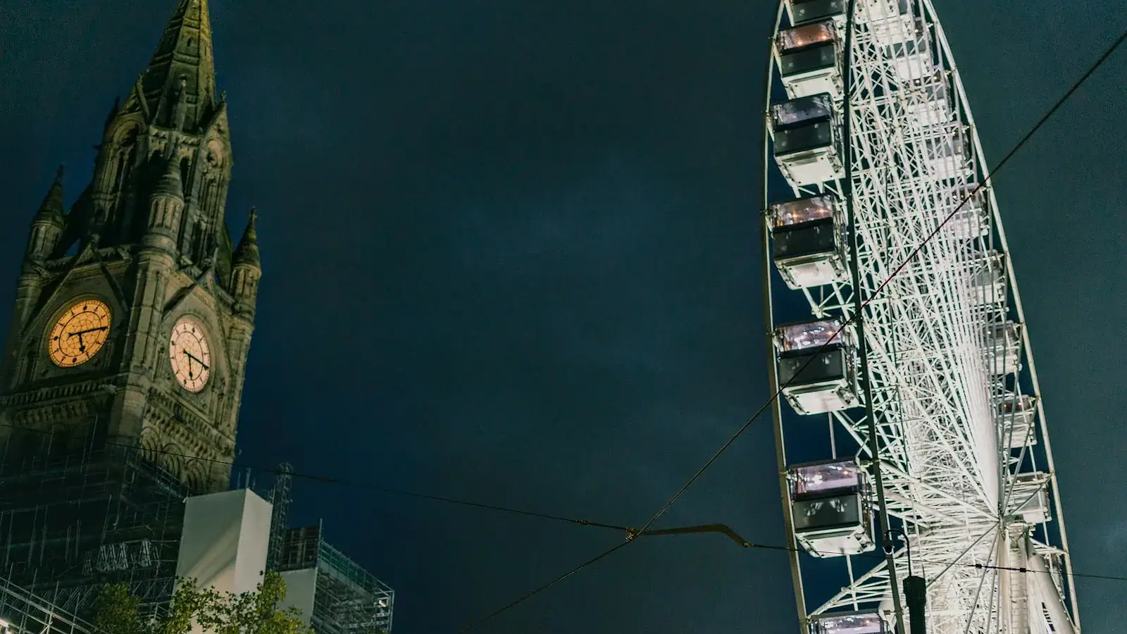 Illuminated clock tower and ferris wheel at night