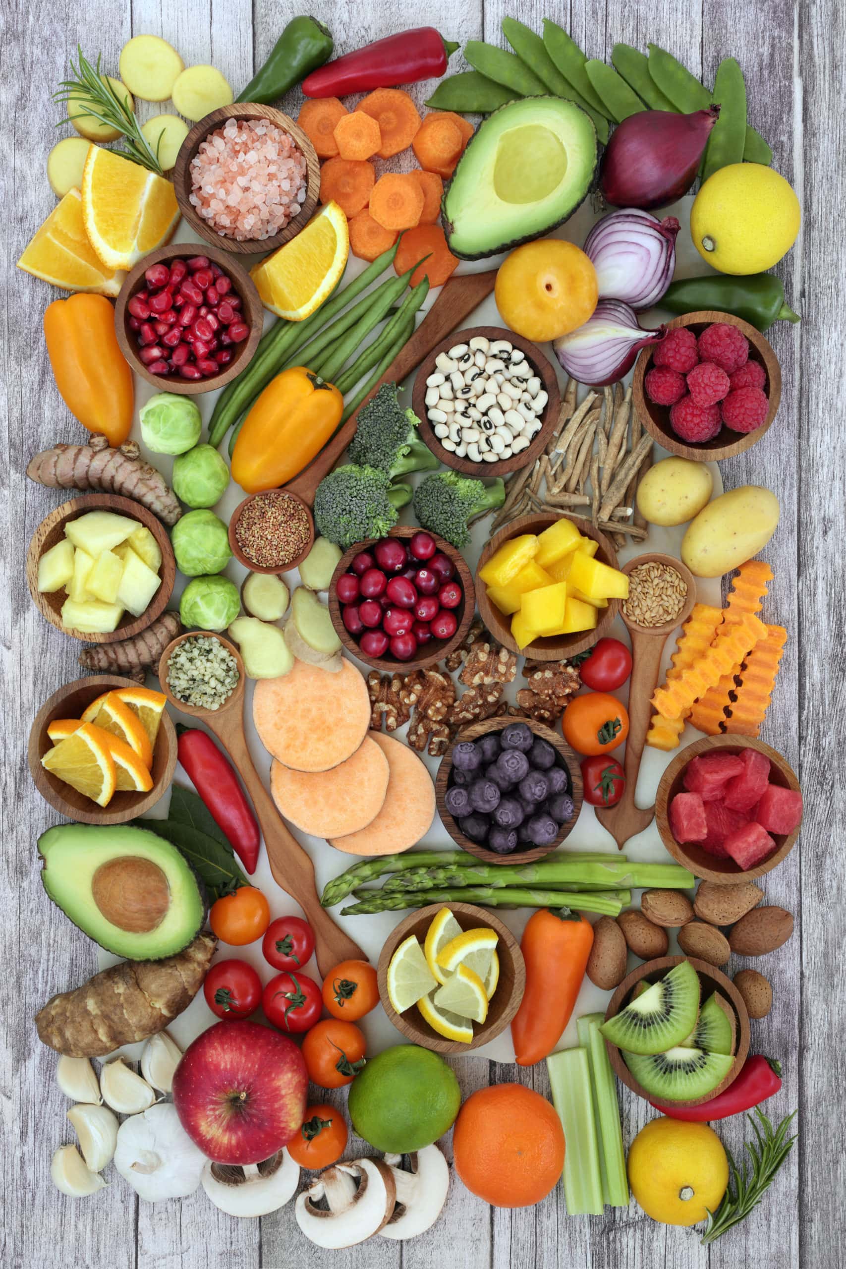 an assortment of fruits, vegetables, and grains, spread across a grey background