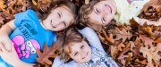 Three kids laying in fall leaves