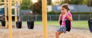 Sad girl sits alone on school swing set