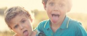 Two male toddlers sticking out their tongues