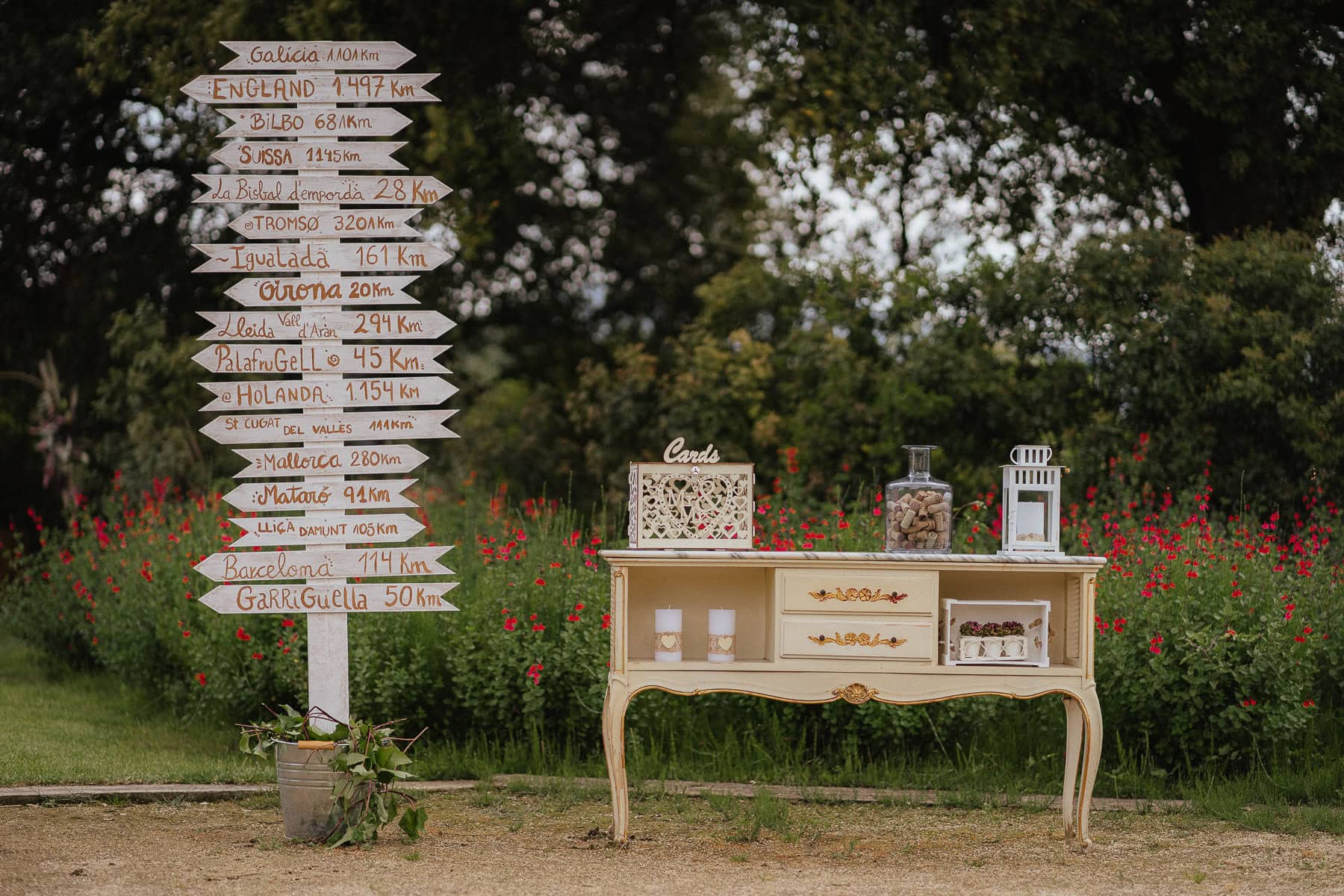 Wedding decoration featuring a sign with different travel destinations and a beautiful rustic piece of furniture