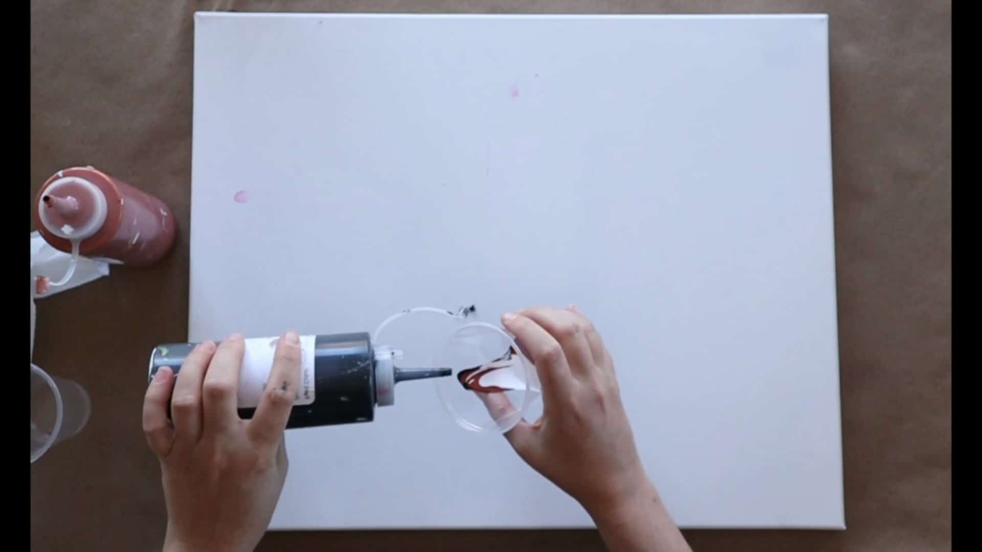 pouring fluid paint into cup for acrylic pour painting