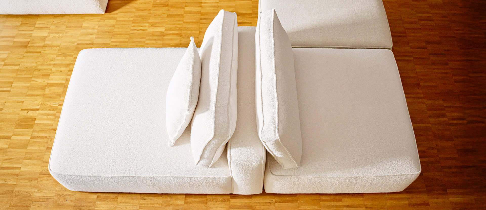 Weißes Sofa mit Kissen auf Laminatboden – hochwertige Einrichtungsideen von Freischem. Modulsofa EPIC Sophisticated Living – flexibel kombinierbar in Meckenheim